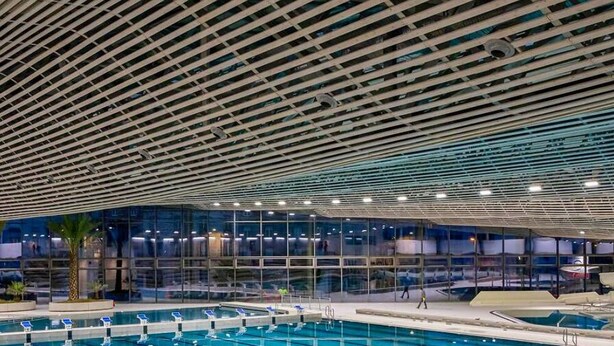 An indoor swimming pool with a modern ceiling design, glass walls, and multiple lanes. - L'Éclat Champenois - Gare/Arena (Reims)