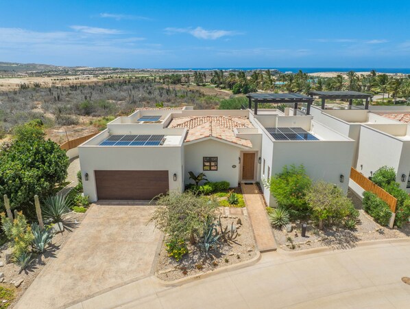 A modern house with a garage, solar panels, and a view of the ocean.