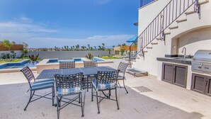 Un patio al aire libre con piscina, zona de barbacoa y un conjunto de comedor.