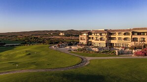 A multi-story building with a courtyard, surrounded by a golf course and desert landscape. - Scenic Views Diamante 2Bdr Condo DRC #306 (Cabo San Lucas)