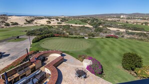 A golf course with a patio area featuring outdoor seating and a view of the course. - Scenic Views Diamante 2Bdr Condo DRC #306 (Cabo San Lucas)