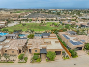 A residential area with multiple houses, a swimming pool, and a view of the ocean.