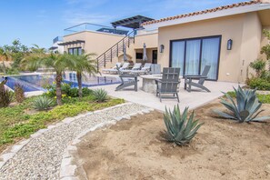 Ein moderner Außenpoolbereich mit Liegestühlen, einem Grill und einer Treppe zu einer zweiten Etage.