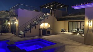 A modern outdoor patio with a pool, a barbecue area, and a seating arrangement.