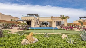 Una casa moderna con piscina, patio y jardín ajardinado.