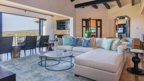 A spacious living room with a large sofa, a coffee table, and a view of the outdoors.