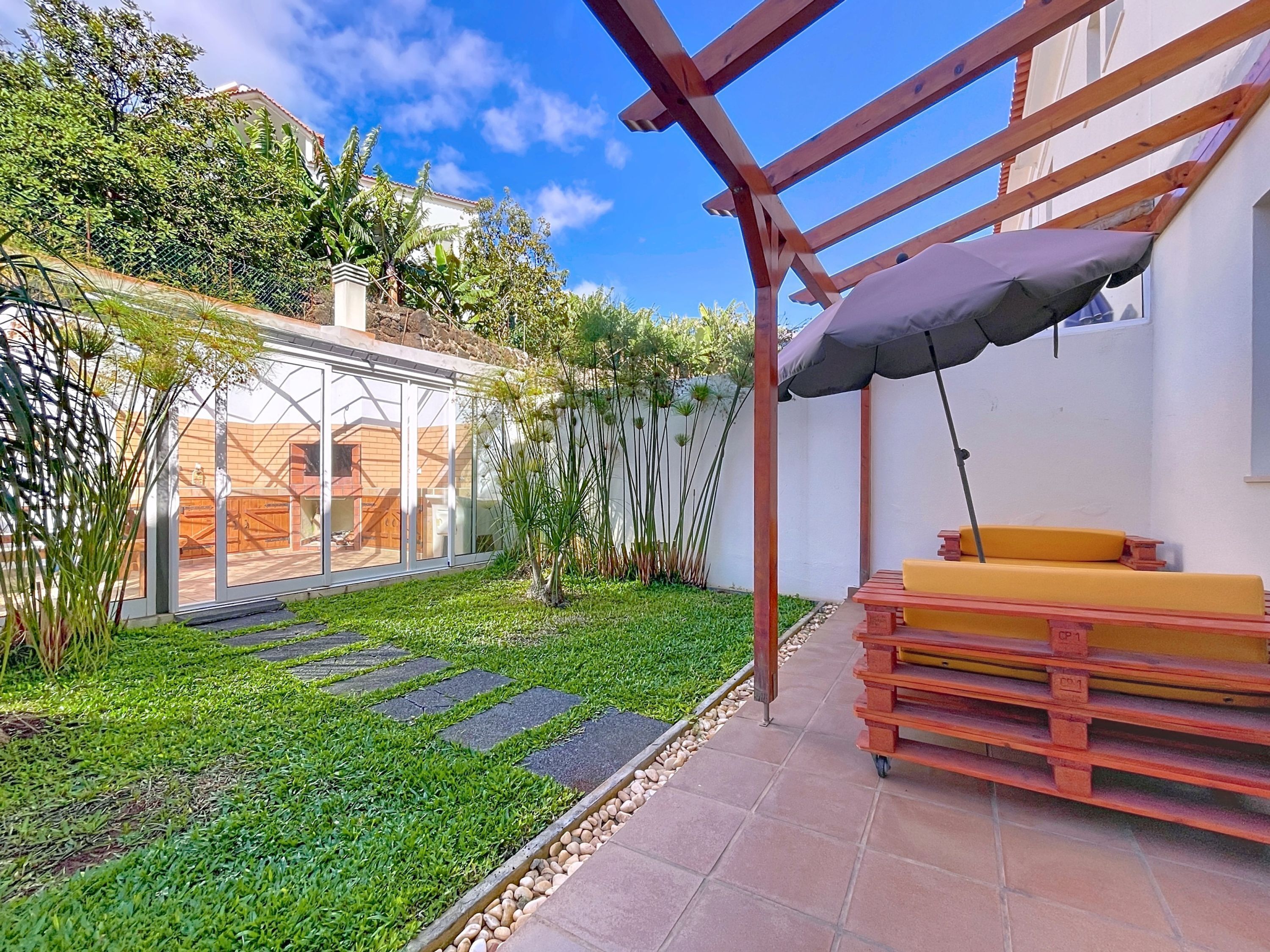A patio with a wooden bench and a pergola.