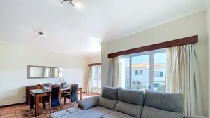 A living room with a grey sectional sofa, a dining table with chairs, a small TV, and a ceiling fan. - Eddys House by Atlantic Holiday (Machico)