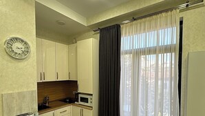Eine kleine Küche mit Holzausstattung, einer Mikrowelle, einem Toaster und einem großen Fenster mit Vorhängen.
