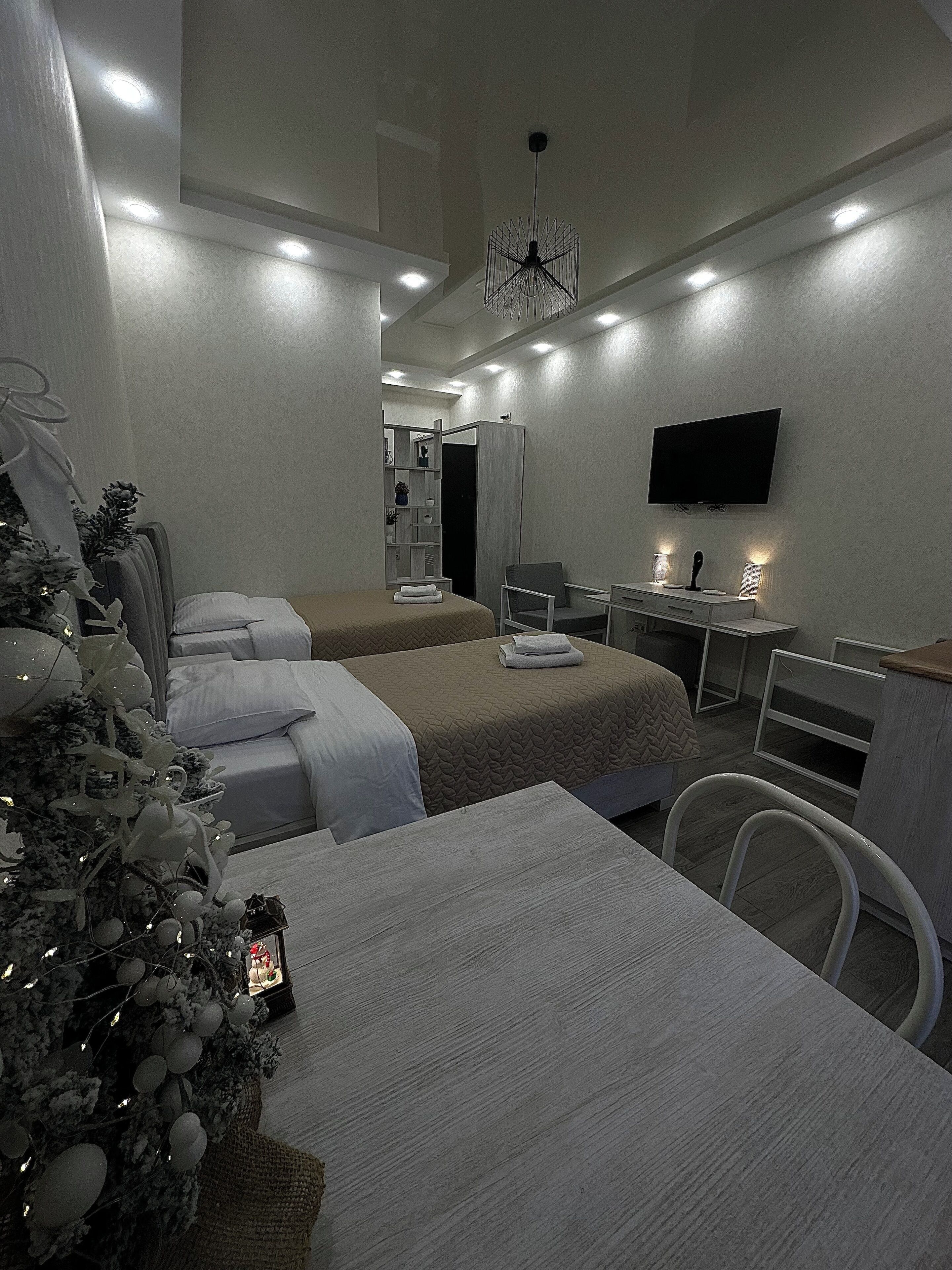 Una habitación de hotel moderna con dos camas, un escritorio, un televisor y un árbol de Navidad.