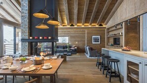 A spacious kitchen with a large island, wooden beams, and a stone accent wall. - Alpine Luxury Chalet Konk in Switzerland (Zermatt)