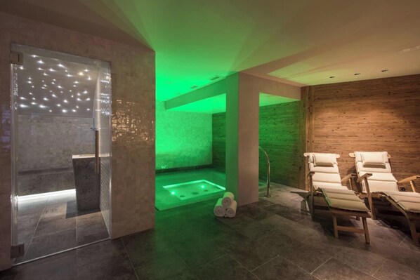 Un cuarto de spa con sauna, camilla de masaje y pared de madera.