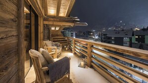 A wooden balcony with a view of a town at night. - Alpine Luxury Chalet Konk in Switzerland (Zermatt)