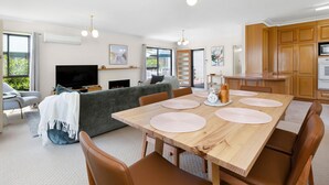 En moderne stue med sofa, fjernsyn og spiseplads med et træbord og stole.