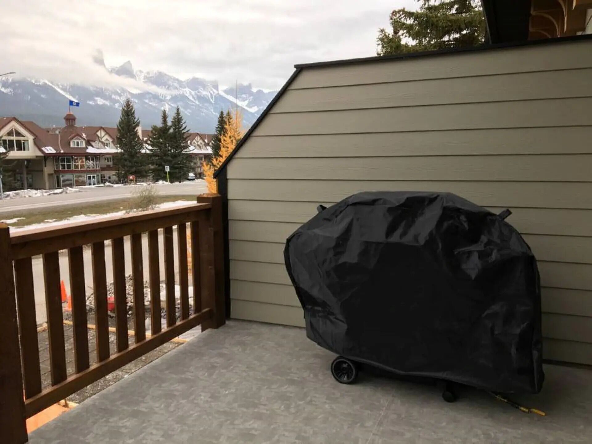 A covered grill on a balcony with a view of snow-capped mountains in the background.