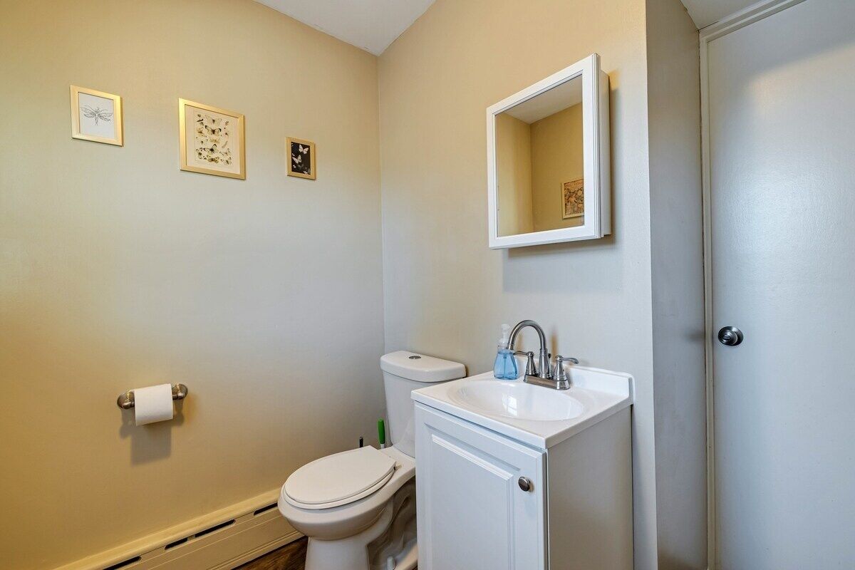 Ein Badezimmer mit Toilette, Waschbecken und drei gerahmten Bildern an der Wand.