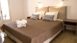Una cama bien hecha con una colcha marrón, dos almohadas con diseños en zigzag y un juego de toallas blancas sobre la cama.