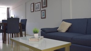 Un salon avec un canapé, une table basse et des tableaux encadrés accrochés au mur.