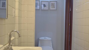 Une salle de bain avec un lavabo, des toilettes et des tableaux encadrés au mur.