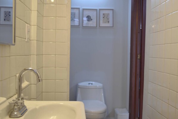 Un baño con lavamanos, inodoro y fotografías enmarcadas en la pared.