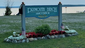 Schild des Plymouth Beach Association, im Hintergrund Blick aufs Wasser.