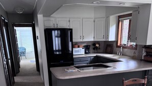 Eine moderne Küche mit einer großen Kochinsel, weißen Schränken und einem schwarzen Kühlschrank.
