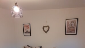 A bedroom with a bed, a hanging light fixture, and two framed pictures on the wall. - MAISONETTE FOR 2 PEOPLE NEAR EUROPA PARK AND RULANTICA  (BINDERNHEIM)