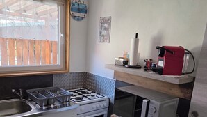 A compact kitchen with a gas stove, oven, microwave, and a refrigerator. - MAISONETTE FOR 2 PEOPLE NEAR EUROPA PARK AND RULANTICA  (BINDERNHEIM)