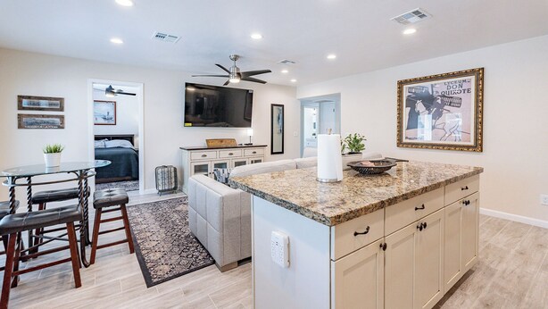 A modern kitchen with a granite countertop, built-in cabinets, and a ceiling fan. - Gilbert AZ 4BR Vacation Home Remodeled Garage (Gilbert)