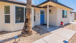 A single-story building with a blue door, large windows, and a covered porch area. - Gilbert AZ 4BR Vacation Home Remodeled Garage (Gilbert)
