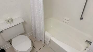 Une salle de bain avec des toilettes, une baignoire et un rideau de douche.