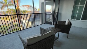 A balcony with wicker furniture and a view of palm trees. - 2-bedroom condo  in Wellen Park Golf and Country Club with Golf Membership (Venice)