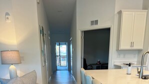 A modern kitchen with a white countertop, bar stools, and a dining area. - 2-bedroom condo  in Wellen Park Golf and Country Club with Golf Membership (Venice)