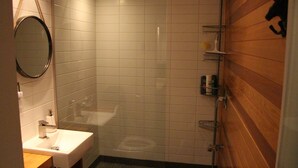 A small, modern bathroom with a sink, mirror, and shower. - Cozy Chalet Near Mont-Sainte-Anne | Sleeps 8–10 | Fireplace | EV Charger (Saint-Ferreol-les-Neiges)