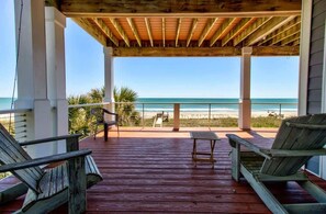 A wooden deck with two lounge chairs and a small table, overlooking a beach with a clear view of the ocean. - One Step Away - Sleeps 28 (Carolina Beach)