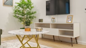 A modern living room with a round marble table, a potted plant, a flat-screen TV, and a white entertainment unit. - Alpine escape villa Vienna apt Gaula Madeira  (Gaula)