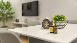 A modern dining area with a white table, a bottle of sauce, and a small plant. - Alpine escape villa Vienna apt Gaula Madeira  (Gaula)