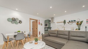 A modern living room with a grey sofa, a dining table with chairs, and a kitchen area in the background. - Alpine escape villa Vienna apt Gaula Madeira  (Gaula)