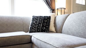 A gray sofa with a patterned pillow and a plain pillow.