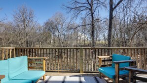 A wooden deck with a sofa and chairs, surrounded by trees.
