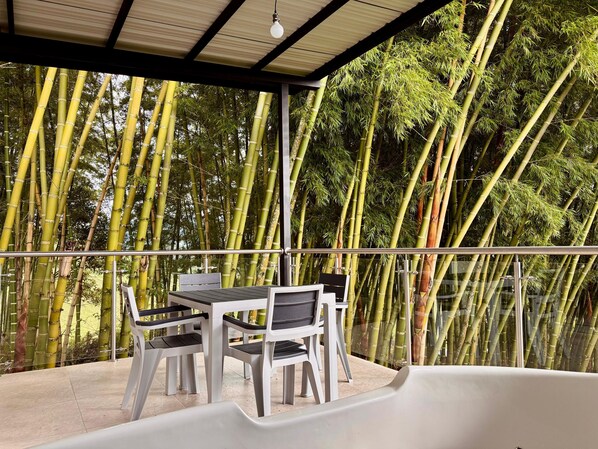 A covered outdoor seating area with a table and chairs, surrounded by tall bamboo trees. - Alto del sion peñol guatape (El Peñol)
