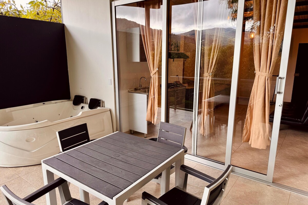 A patio area with a table and chairs, a hot tub, and a sliding glass door leading to a balcony.