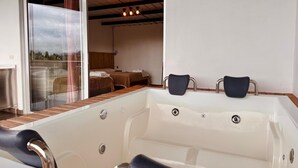 A modern bathroom with a bathtub, two chairs, and a glass door leading to a bedroom with two beds. - Alto del sion  peñol guatape  (El Peñol)