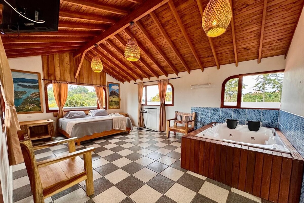 A cozy room with a bed, a wooden bench, a bathtub, and a checkered floor.