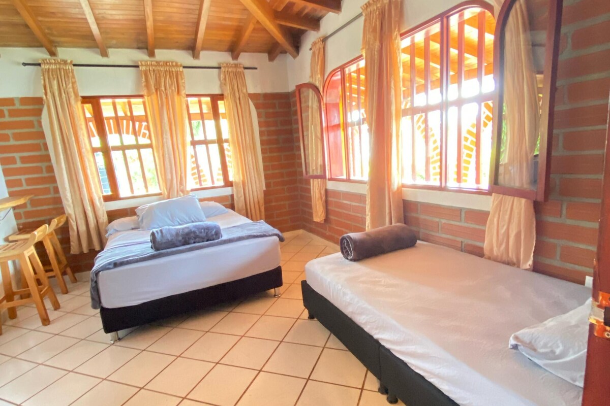 A room with two beds, a wooden ceiling, and brick walls.