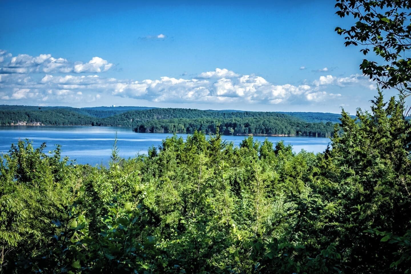 A lake surrounded by dense forest and hills.