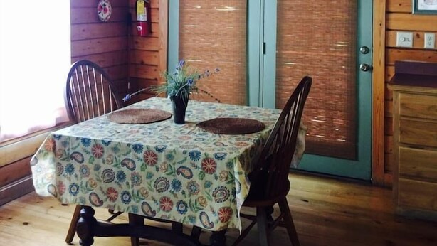 A wooden interior with a dining table, chairs, and a hanging light fixture.