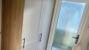A room with a sliding glass door, a wooden wardrobe, and a light-colored floor. - Charming 2-bed Chalet in Tuxford (Newark)