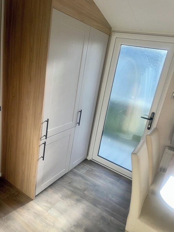 A room with a sliding glass door, a wooden wardrobe, and a light-colored floor. - Charming 2-bed Chalet in Tuxford (Newark)