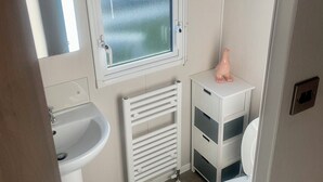 A compact bathroom with a window, a sink, a toilet, and a radiator. - Charming 2-bed Chalet in Tuxford (Newark)